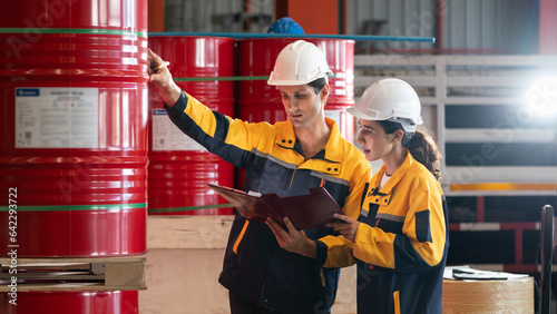 Two factory workers or inventory inspector conduct professional inspection on hazardous chemical barrels in warehouse, chemistry storage workplace and industrial profession concept. Exemplifying photo