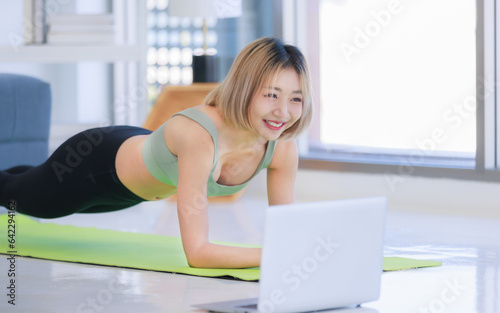 Asian young beautiful female athlete teenager in sportswear sport bra legging stretching body lay down planking on elbows exercising practicing working out abdomen abs on yoga pilates in living room.