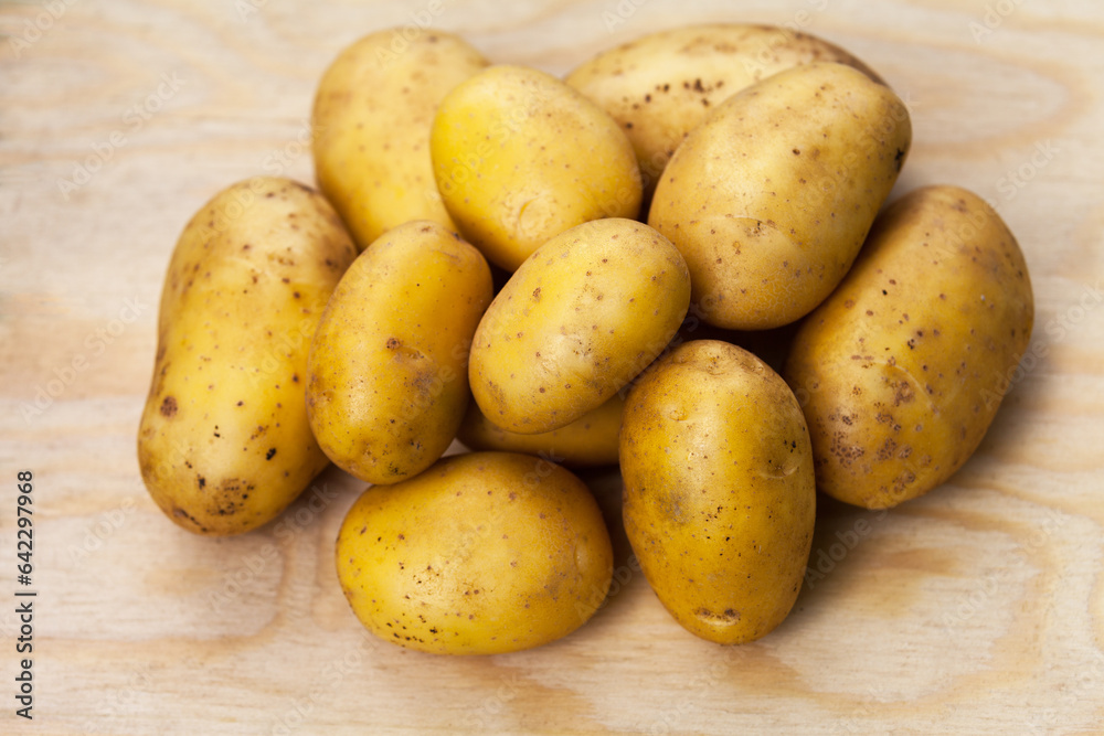 Freshly picked potatoes lie in a pile on a wooden background. Organic healthy food. New crop of young potatoes. Sale of farm natural products Freshly picked potatoes lie in a pile on a wooden background. Organic healthy food. New crop of young potatoes. Sale of farm natural products