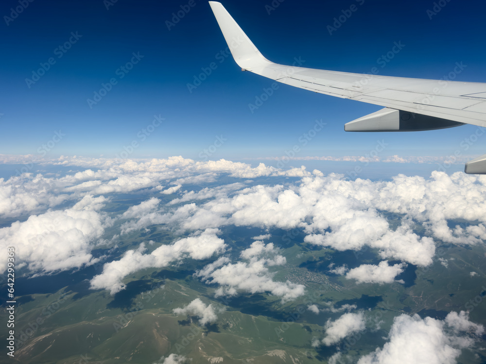 White wing from airplane window with mountain range below on sunny day ...
