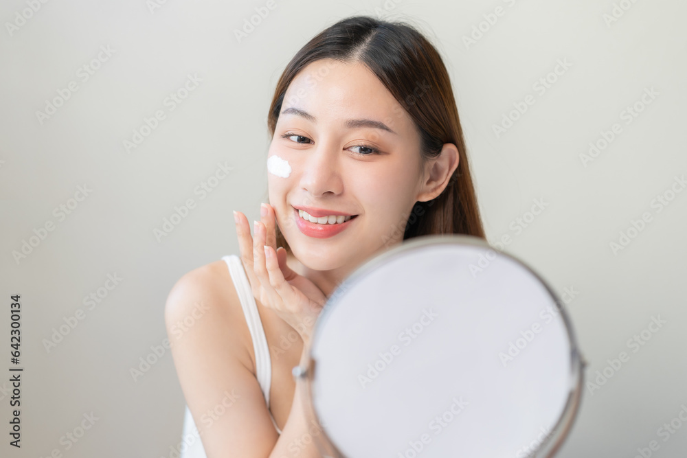 Fresh healthy skin, beautiful smile asian young woman, girl happy applying moisturizer on her face, putting cream treatment before makeup cosmetic routine isolated on white background. Facial Beauty. Fresh healthy skin, beautiful smile asian young woman, girl happy applying moisturizer on her face, putting cream treatment before makeup cosmetic routine isolated on white background. Facial Beauty.