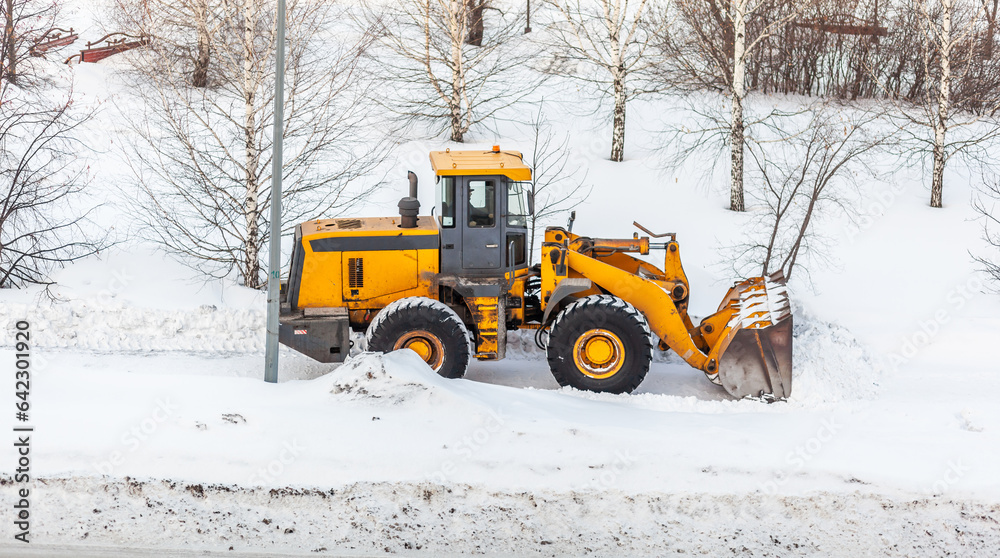 Snow clearing. Tractor clears the way after heavy snowfall. A large orange tractor removes snow from the road and clears the sidewalk. Cleaning roads in the city from snow in winter. Snow clearing. Tractor clears the way after heavy snowfall. A large orange tractor removes snow from the road and clears the sidewalk. Cleaning roads in the city from snow in winter.