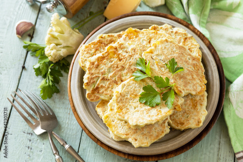 Cauliflower vegetable fritters with cheese on a rustic kitchen table. Fried vegetarian cutlets or pancakes.