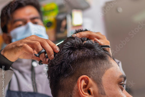 Young man cutting hair at the modern barber shop