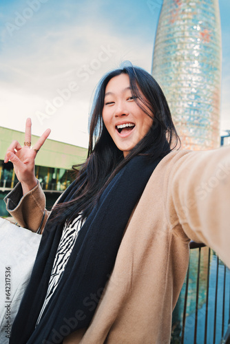 Quadro su tela Vertical individual close up portrait of a happy asian young lady taking a selfie photo with an smartphone