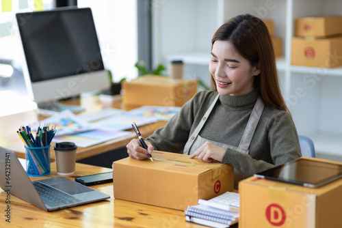 Entrepreneurs start small businesses. Woman doing online sales startup business checking internet orders on laptop and packing parcels for delivery. © Kainnika