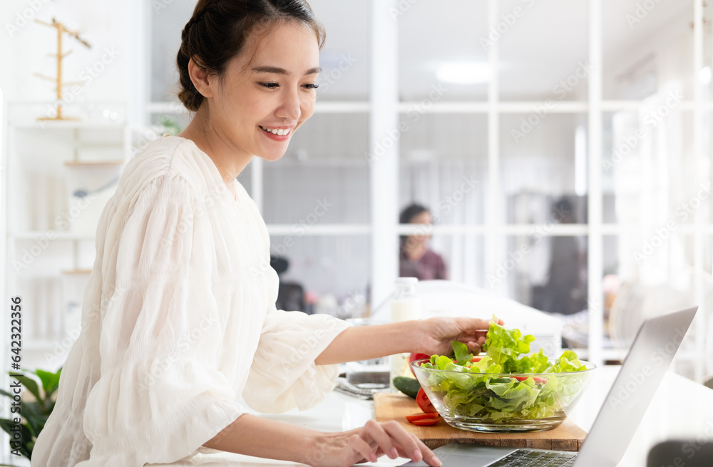 Young woman using laptop computer to take part in online culinary workshop, learning vegan cuisine recipes on web from home. Millennial lady watching cooking tutorial on internet Young woman using laptop computer to take part in online culinary workshop, learning vegan cuisine recipes on web from home. Millennial lady watching cooking tutorial on internet