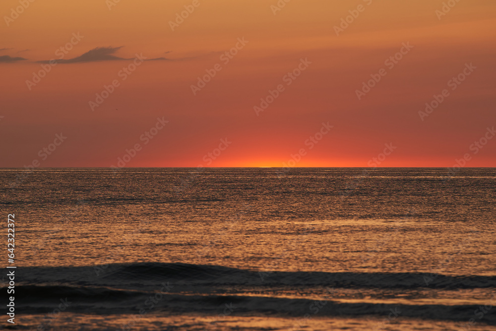 Radiant Sunset Over the Ocean. The Glowing Sun Sinking on the Horizon