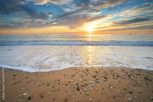 Sand and rocks on seashore at sunset