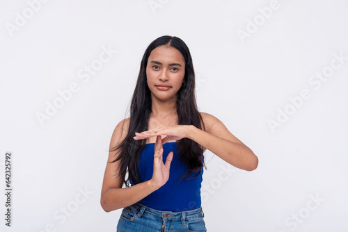 A serious young Filipino woman adamantly requests for a time out or break. Gesturing with her hands. Isolated on a white background. photo