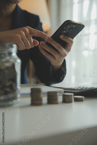 saving money and accounting concept. business man putting coin insert to jar and make acounting book for finance management to investment and saving. photo