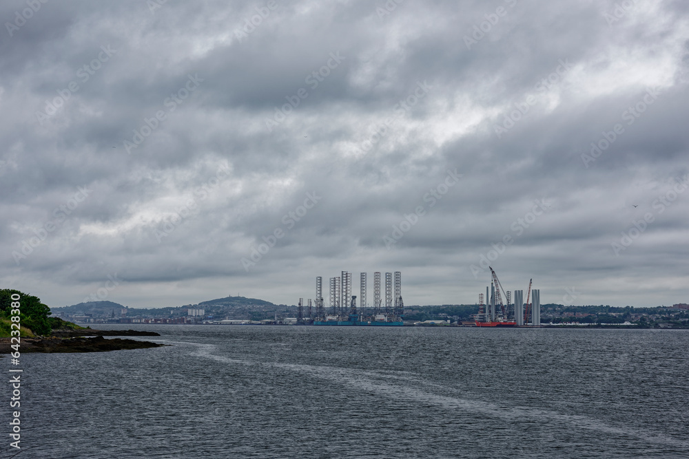 The view of the Port of Dundee from Tayport the other side of the Tay Estuary on a dark Rainy day in July with Oil Rigs lining the Wharfs of the Port.