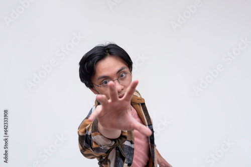 Suspensful scene of a young asian man tries to reach out in the nick of time. Isolated on a white backdrop. photo