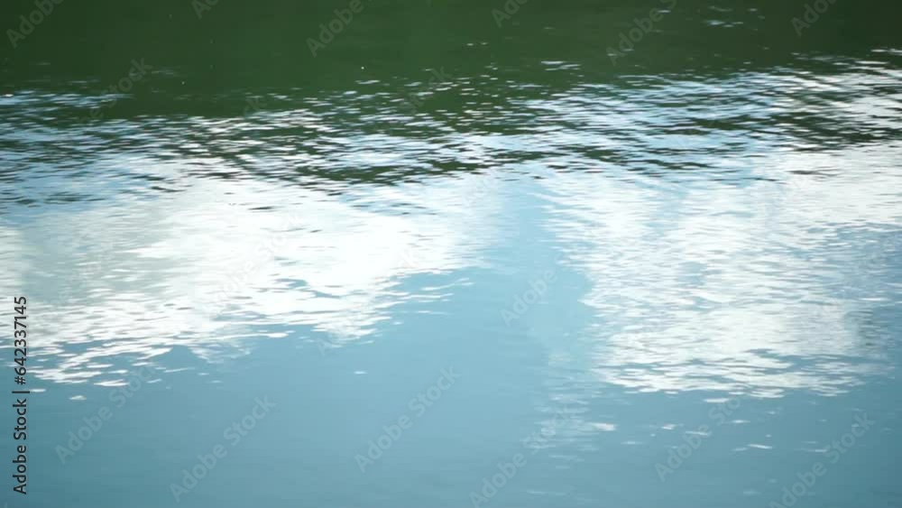 clouds in blue sky reflect on lake, movement of wave on water surface, white fluffy clouds. Ripples on water surface with the reflection of sky and clouds. Holiday, vacation and recreational concept. clouds in blue sky reflect on lake, movement of wave on water surface, white fluffy clouds. Ripples on water surface with the reflection of sky and clouds. Holiday, vacation and recreational concept.