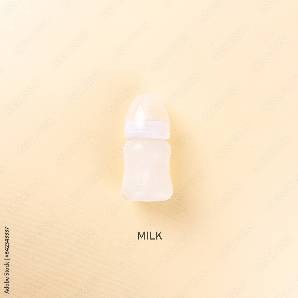 Baby's milk bottle on a yellow background. Concept, top view, copy space.