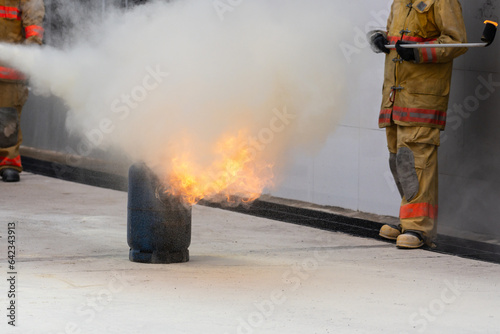 Showing how to use a fire extinguisher on a training fire for employees industry.Firefighter working on the fire site.Fire fighter concept.