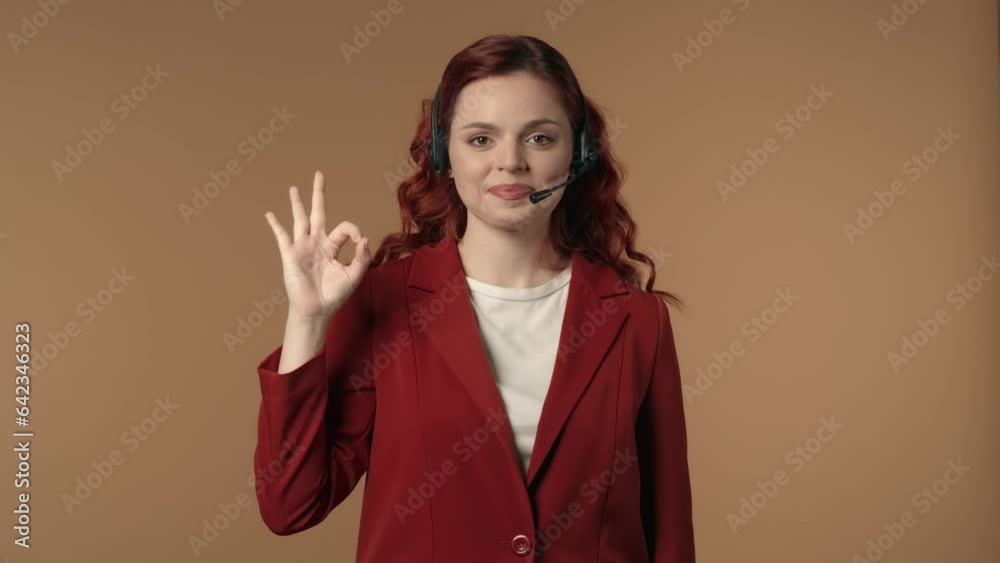 Medium isolated video of a happy and relaxed young woman in a call center headset showing an 'OK' sign with her right hand. Medium isolated video of a happy and relaxed young woman in a call center headset showing an 'OK' sign with her right hand.