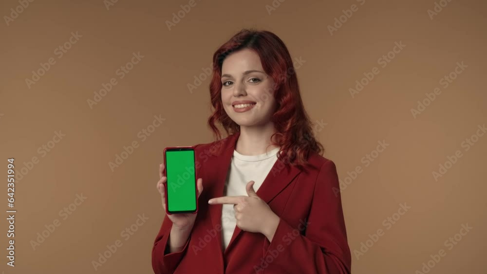 Medium isolated video of a young woman smiling at the camera and pointing at the phone with advertising area, workspace mock up. Medium isolated video of a young woman smiling at the camera and pointing at the phone with advertising area, workspace mock up.