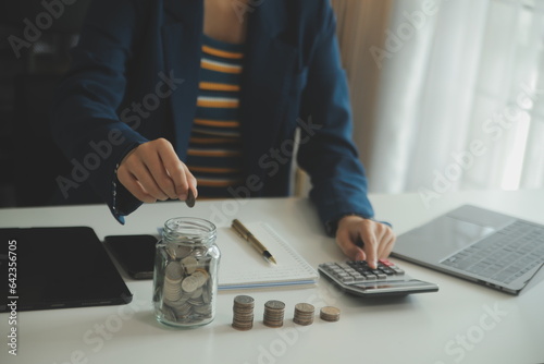 saving money and accounting concept. business man putting coin insert to jar and make acounting book for finance management to investment and saving. photo