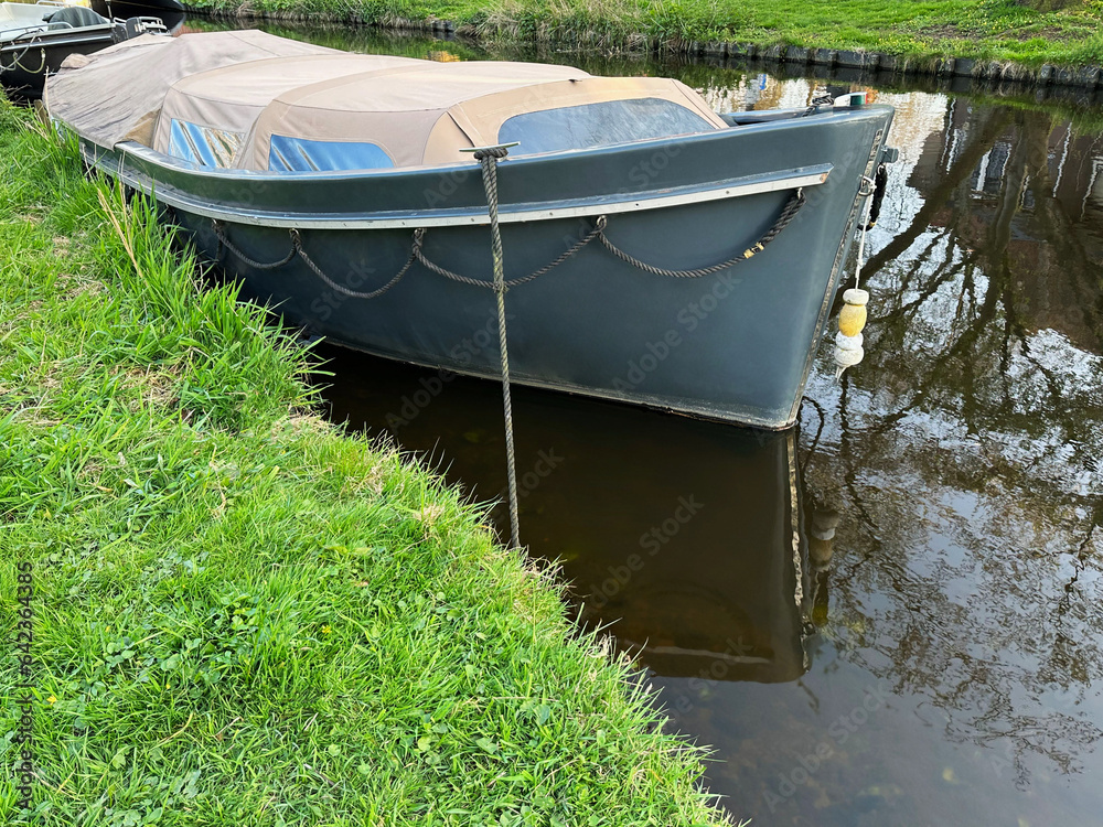 View of canal with moored boat near green shore View of canal with moored boat near green shore