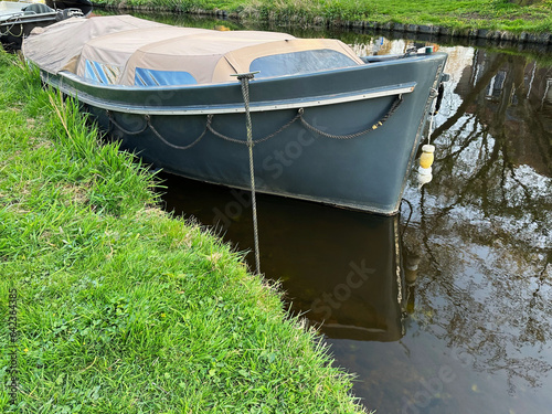 View of canal with moored boat near green shore