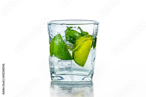 A glass of water with lime and ice on a white background.