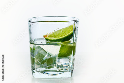 A glass of water with lime and ice on a white background.
