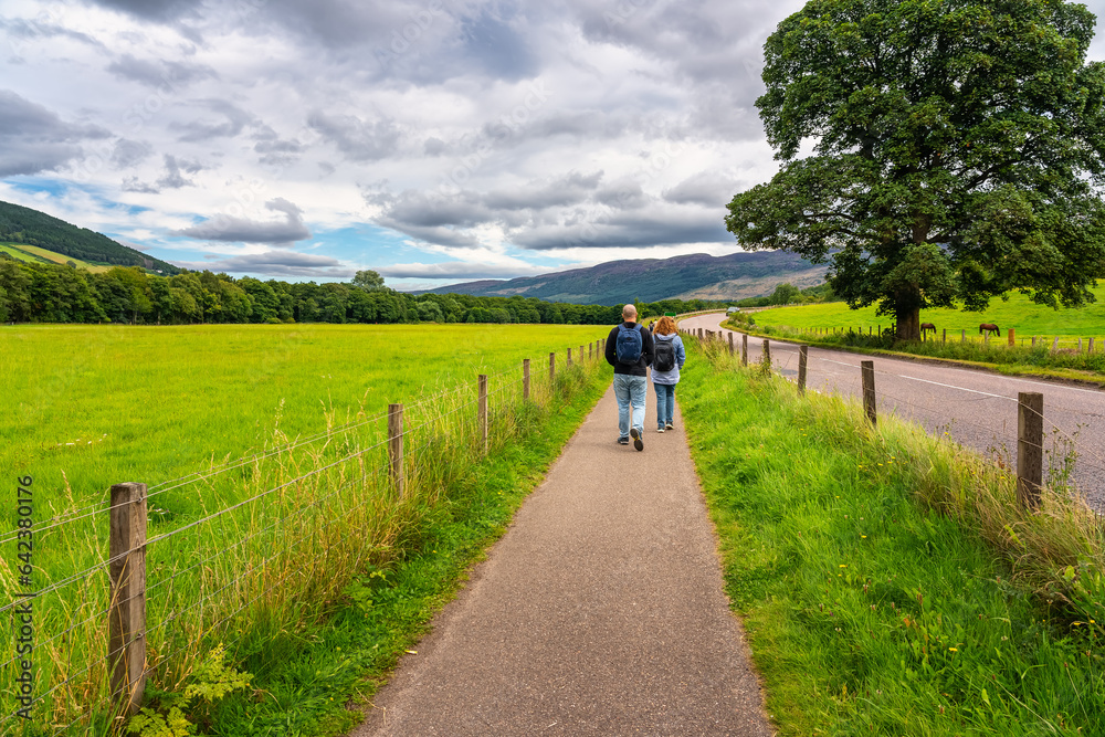 People walking along a roadside path in the highlands of Scotland, UK. People walking along a roadside path in the highlands of Scotland, UK.