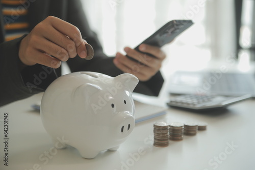 saving money and accounting concept. business man putting coin insert to jar and make acounting book for finance management to investment and saving. photo