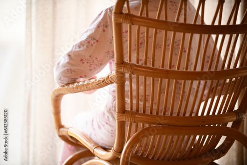 パジャマ姿で籐椅子に座るシニアの女性