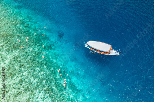 Aerial view sailing boat next to reef. Bird eye view, water sport theme. Snorkel excursion, recreational dive with tourist. Luxury water sport outdoors activity in Maldives. Exotic travel landscape © icemanphotos
