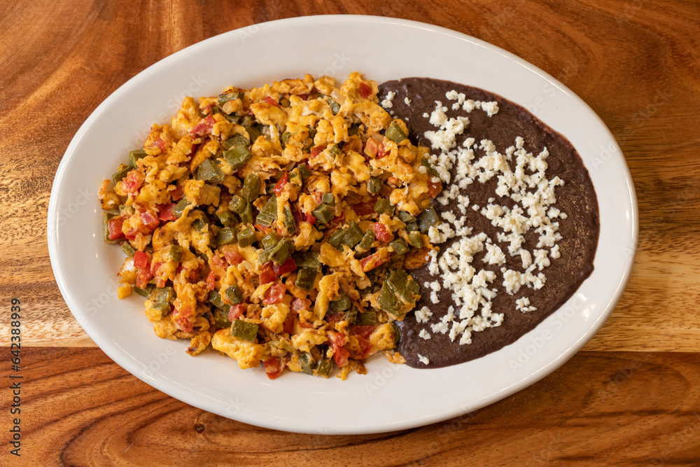Delicious fried egg and black beans corn tortillas with grated cheese served on plate Delicious fried egg and black beans corn tortillas with grated cheese served on plate
