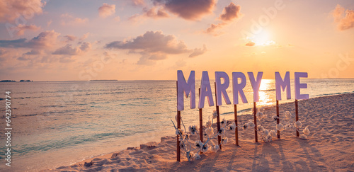 Fototapeta Naklejka Na Ścianę i Meble -  Love couple romantic proposal on paradise beach in island Maldives. Panoramic sunset of Marry Me sign at beach background. Romance colorful sky sea. Marriage proposal, honeymoon tropical destination