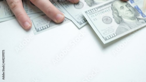 A mans hands rake hundred-dollar bills from the table. Greed, accumulation of money. photo