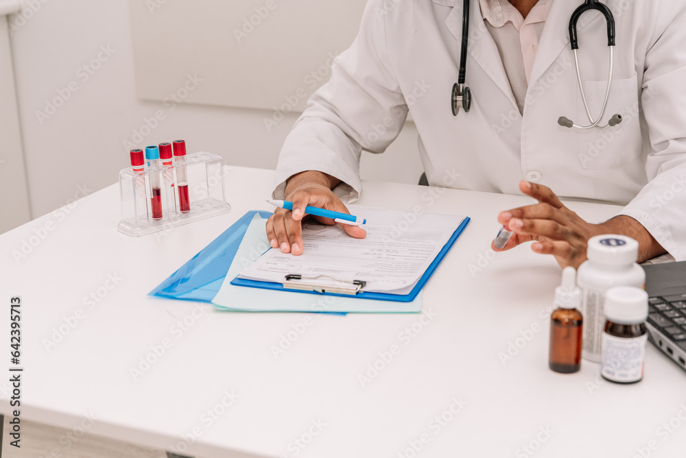 Focused doctor with blood test tube writing information in form after blood test Focused doctor with blood test tube writing information in form after blood test