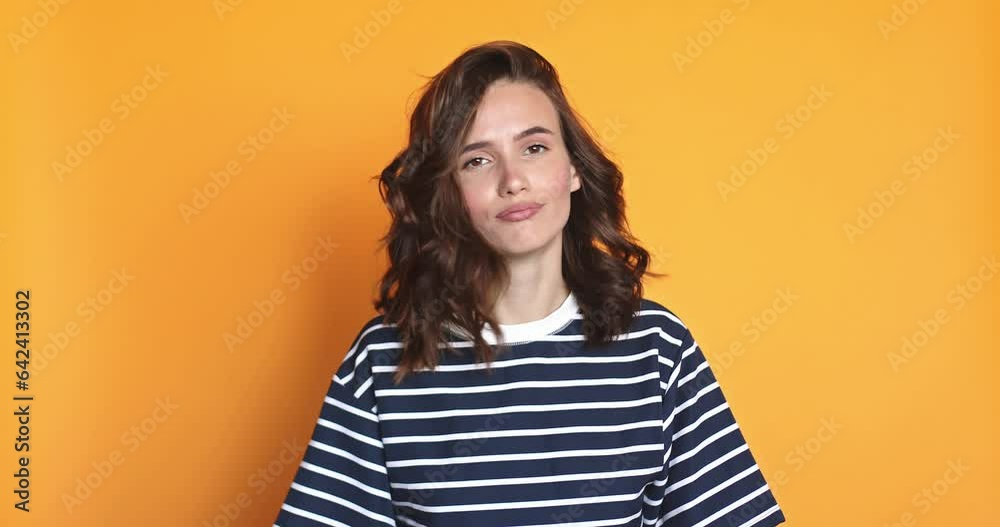 Brunette curly woman looking camera pointing fingers herself ask me no i do not need it. Girl waving her hands and say no isolated on yellow background.