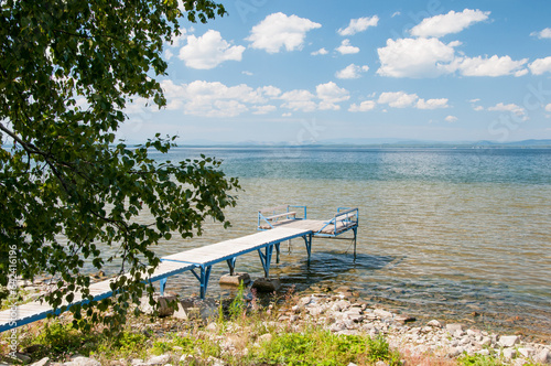 Landscape view of lake Uvildy in summer with a pier on its shore, South Ural, Russian Federation photo