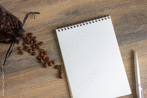 Notepad and coffee beans scattered on the wooden table