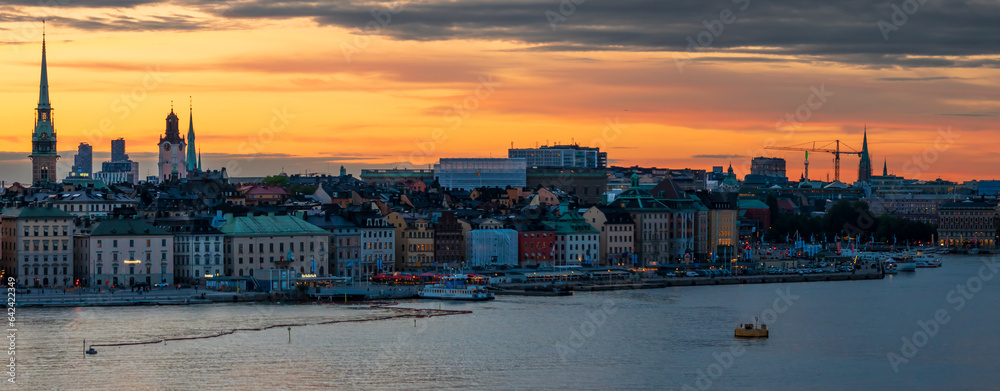 Εκτύπωση καμβά Panoramic view of Stockholm's old town, churches and seafront on a summer evening, with orange sky and colorful buildings