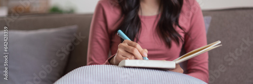 Women wearing headphone to listening music and writing notes on diary notebook in lifestyle at home