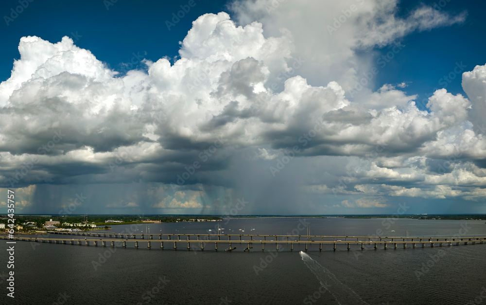 Heavy thunderstorm approaching traffic bridge connecting Punta Gorda and Port Charlotte over Peace River. Bad weather conditions for driving during rainy season in Florida