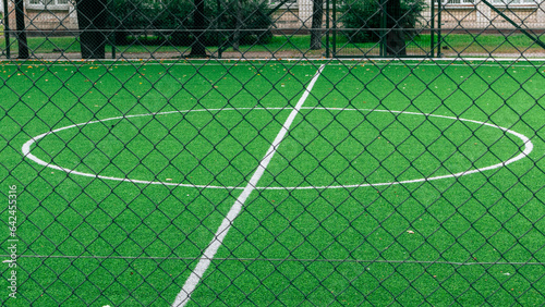 The center of an empty soccer field with an artificial green turf. The marking of the center of the soccer stadium