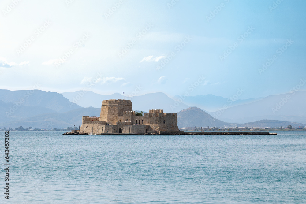 Bourtzi Fortress on a small island in Nafplio surrounded by water with mountains in the background, viewed from the port