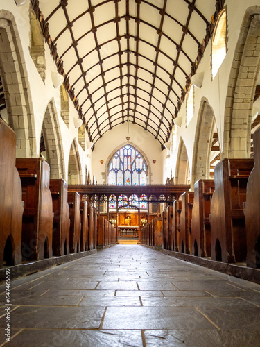 Looking down the stone floored aisle of a small church with rows of pews on either side.