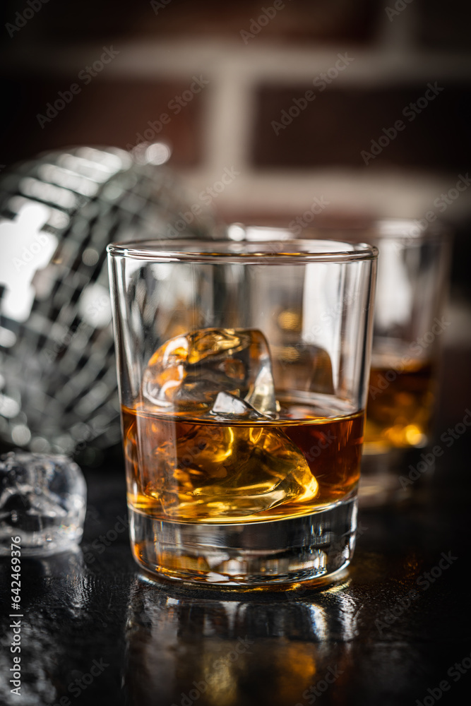 Whiskey with ice in glass on dark background, copy space Whiskey with ice in glass on dark background, copy space