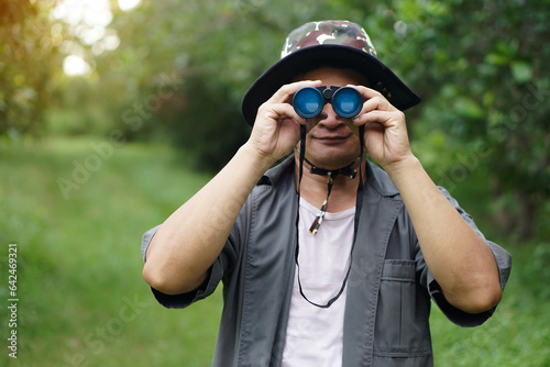 Asian man ecologist use binocular to survey nature in forest. Concept, nature exploration. Ecology study. Pastime activity, lifestyle. Explore environment. Traveling alone              photo