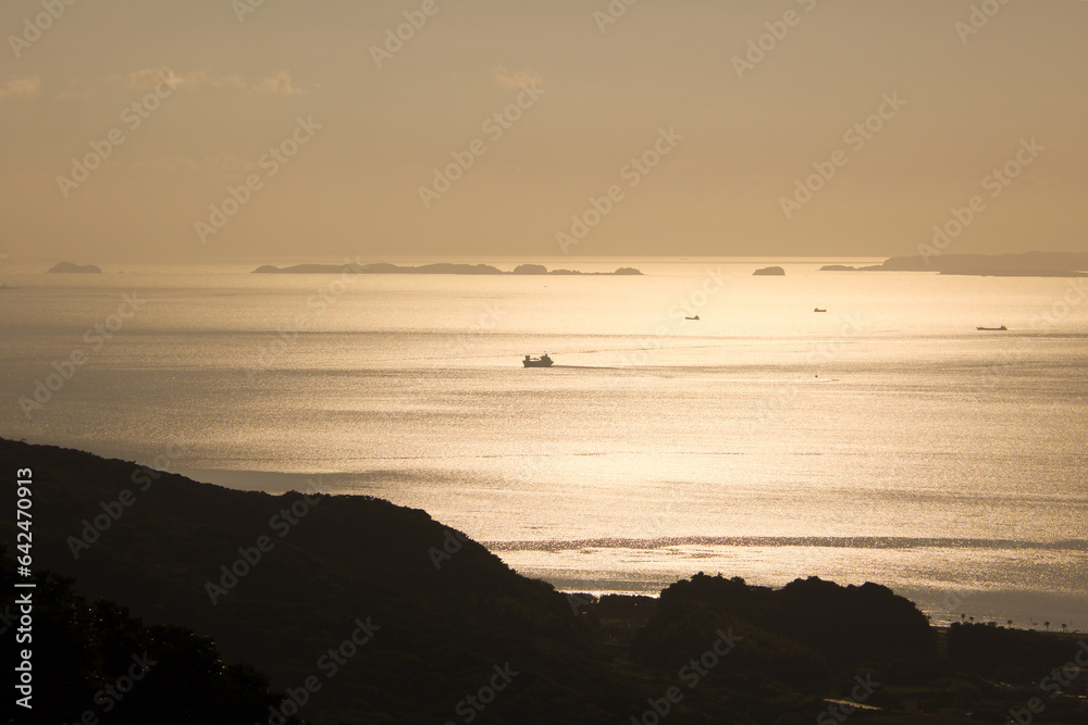 夕暮れ時の黄金色に輝く海と漁船