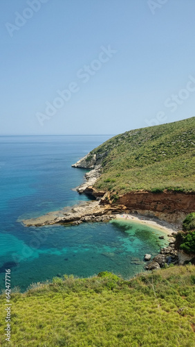 bay with blue water and cliffs, Sicilian beautiful beach and blue water near a cliff, blue sea in the middle of rocks. Mediterranean sea. sandy coastline and blue water is seen from the top of a cliff