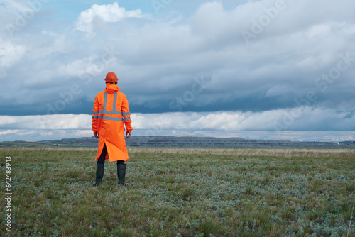 A man in an orange raincoat and helmet on the background of the mine