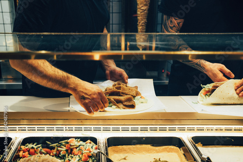 Hands of a clerk making delicious kebab rolls photo